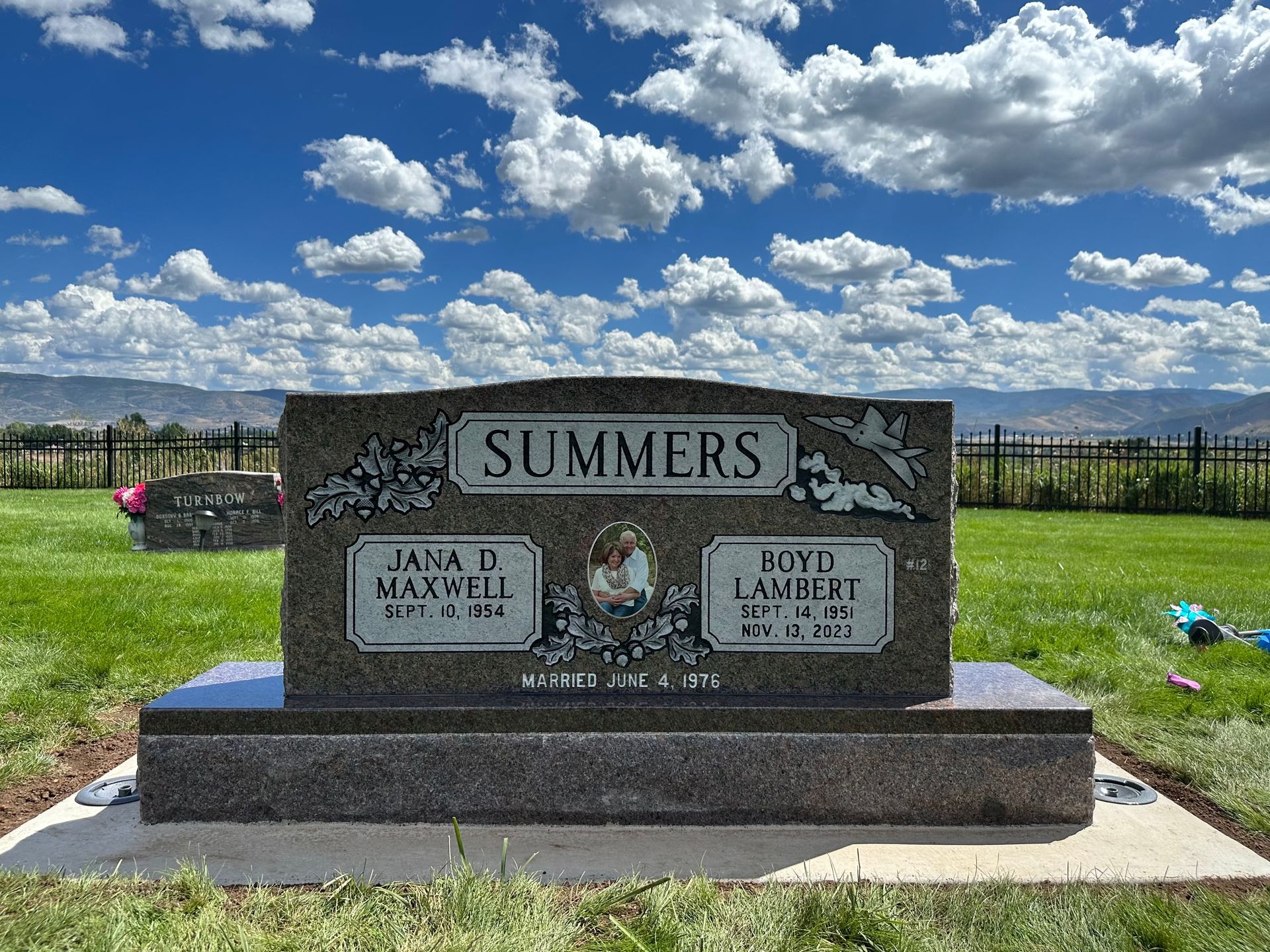 Headstone for the Summers family in a cemetery. Blue sky, white clouds, and green grass in the background.