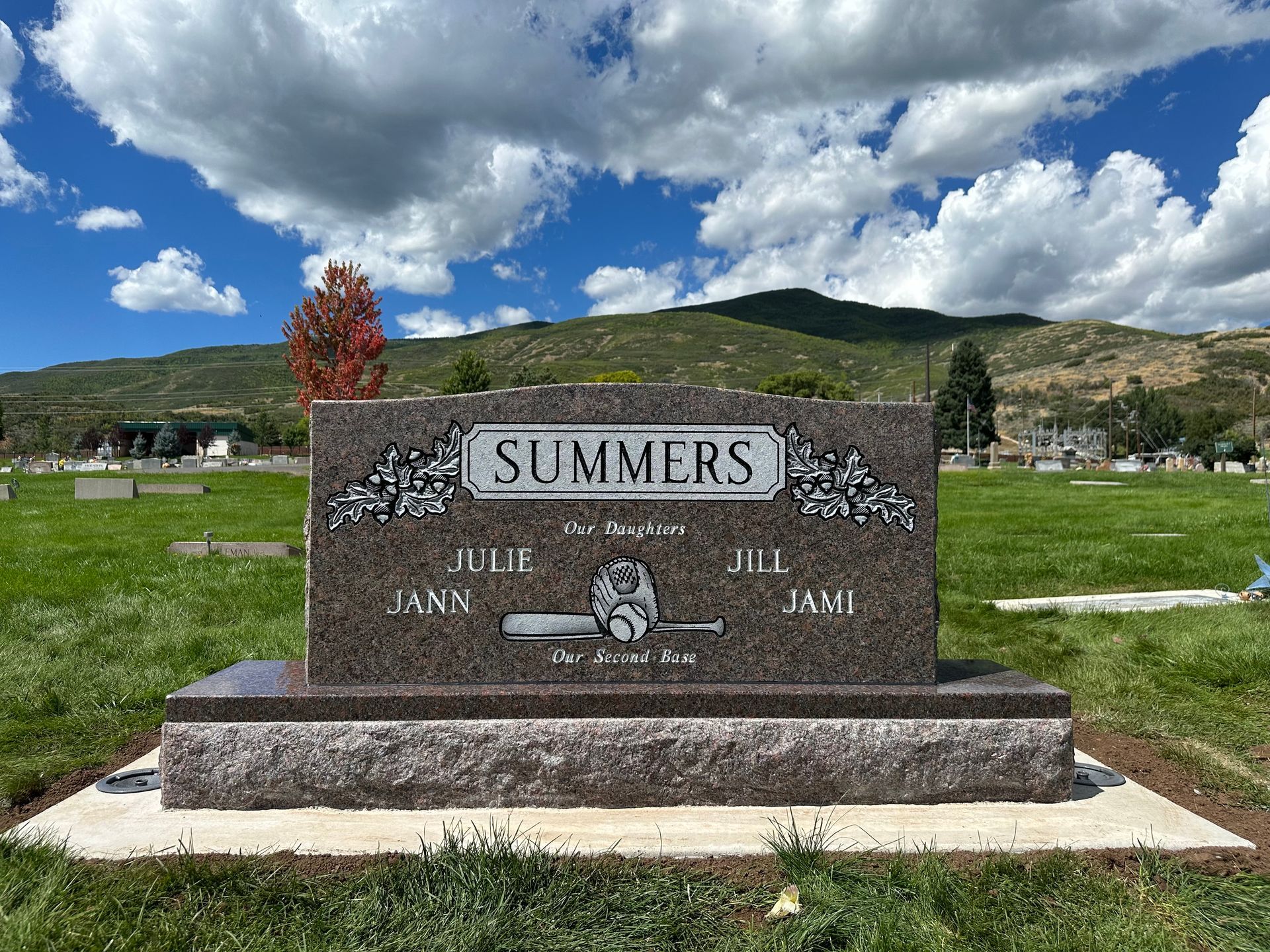 Headstone: Summers, baseball and names, in a cemetery, with mountains and sky in the background.