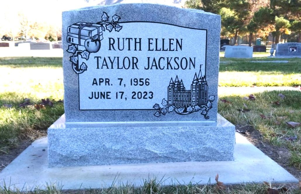 Tombstone of Ruth Ellen Taylor Jackson, born 1956, died 2023, gray granite, floral design, outdoor cemetery setting.