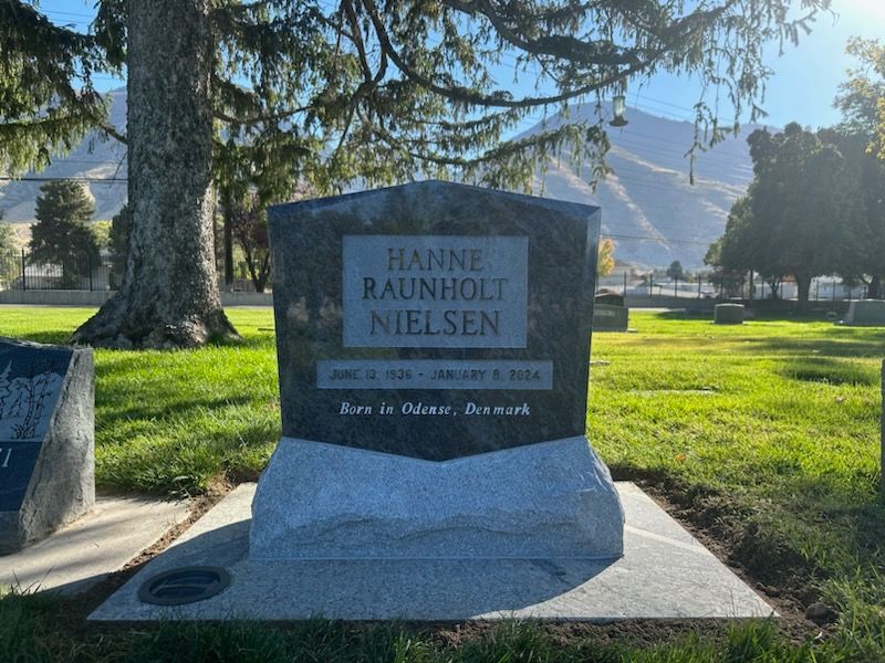 Grave of Hanne Raunholt Nielsen at a cemetery, with a mountain backdrop.