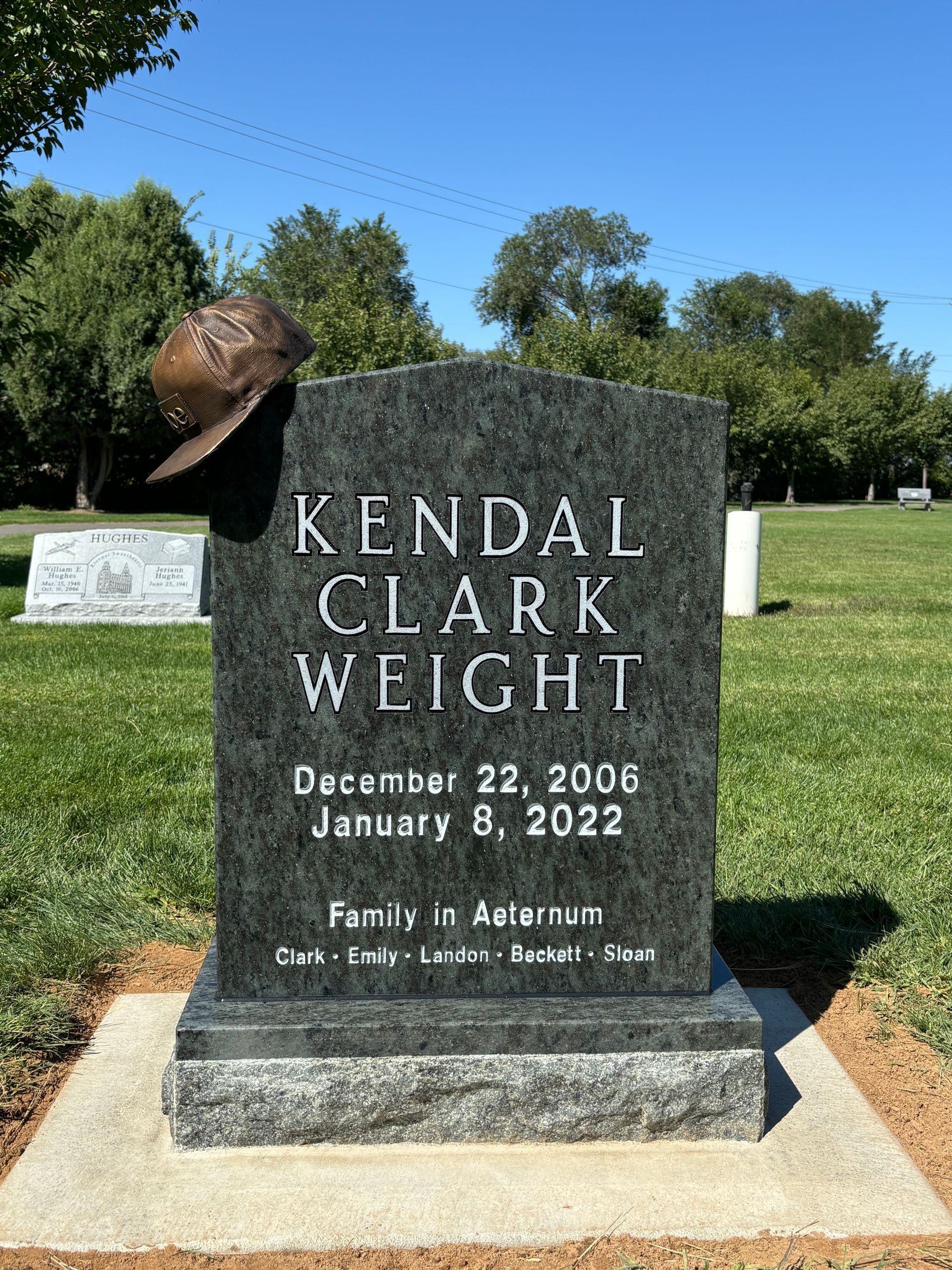 Headstone of Kendal Clark Wright with a cowboy hat, dates 2006-2022, in a sunny cemetery.
