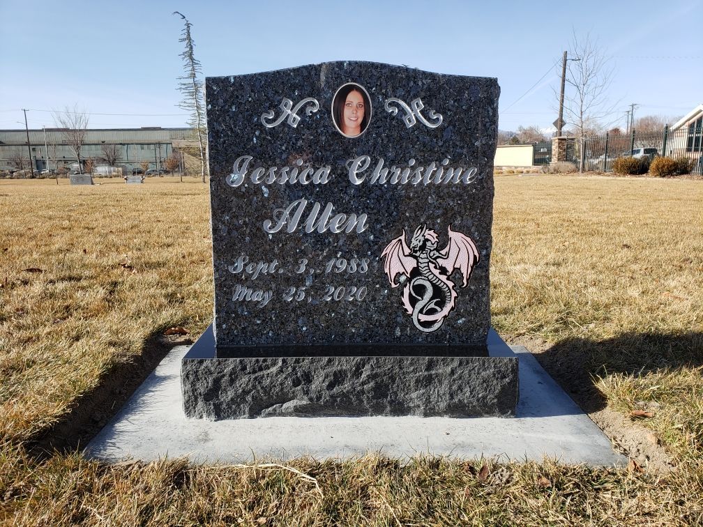 Headstone for Jessica Christine Allen, black granite with a photo and dragon design. In a cemetery.