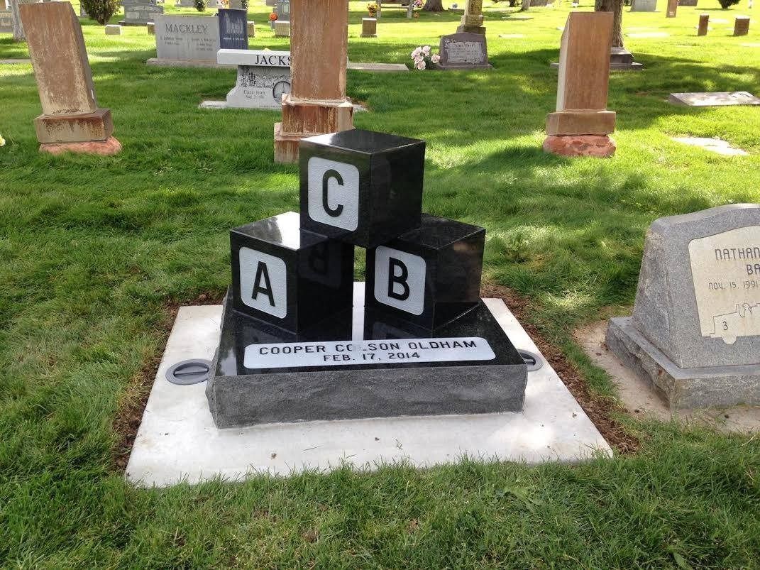 Grave marker with ABC blocks in a cemetery. Blocks are black with white letters A, B, C.