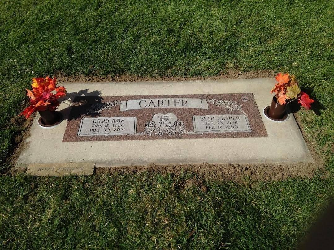 Gravestone in a grassy setting with flowers; bears the name 