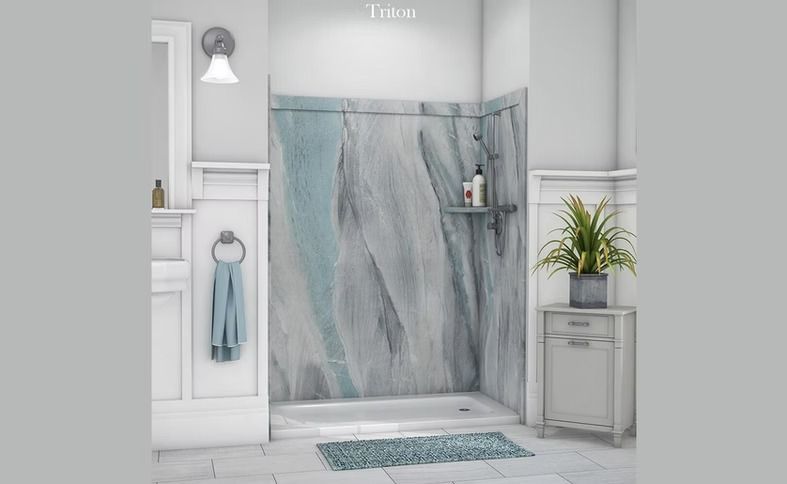 Bathroom with a shower featuring blue and grey patterned walls, a white sink, and a decorative plant.