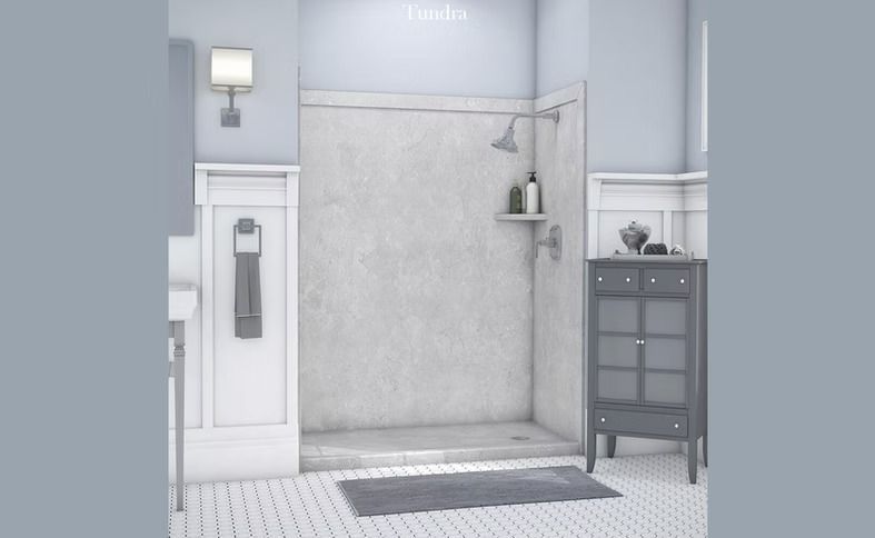 A modern bathroom with a gray shower stall, blue-gray walls, and a dark gray cabinet. White tile floors, a rug, and a towel are visible.