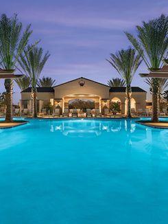 A large swimming pool surrounded by palm trees in front of a building.