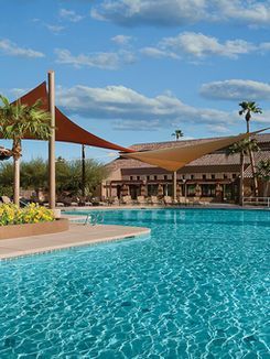A large swimming pool surrounded by palm trees and umbrellas.