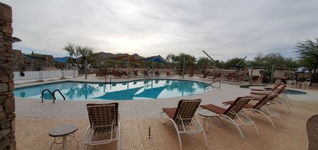 A large swimming pool surrounded by lawn chairs and umbrellas.