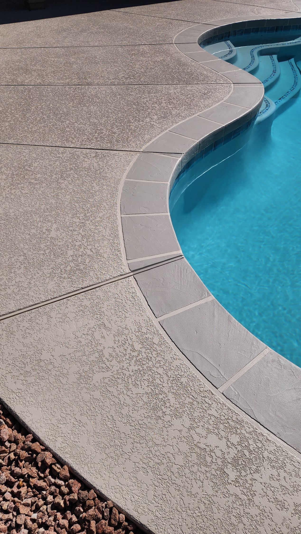 A swimming pool with a concrete deck and a blue water.