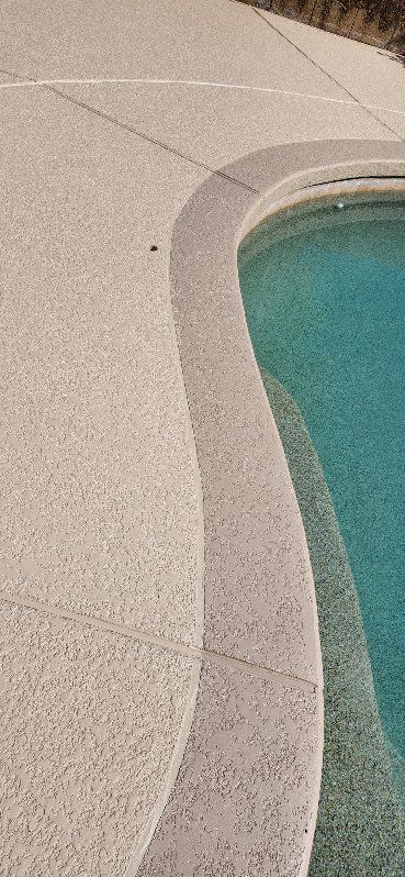 A swimming pool with a concrete walkway surrounding it.
