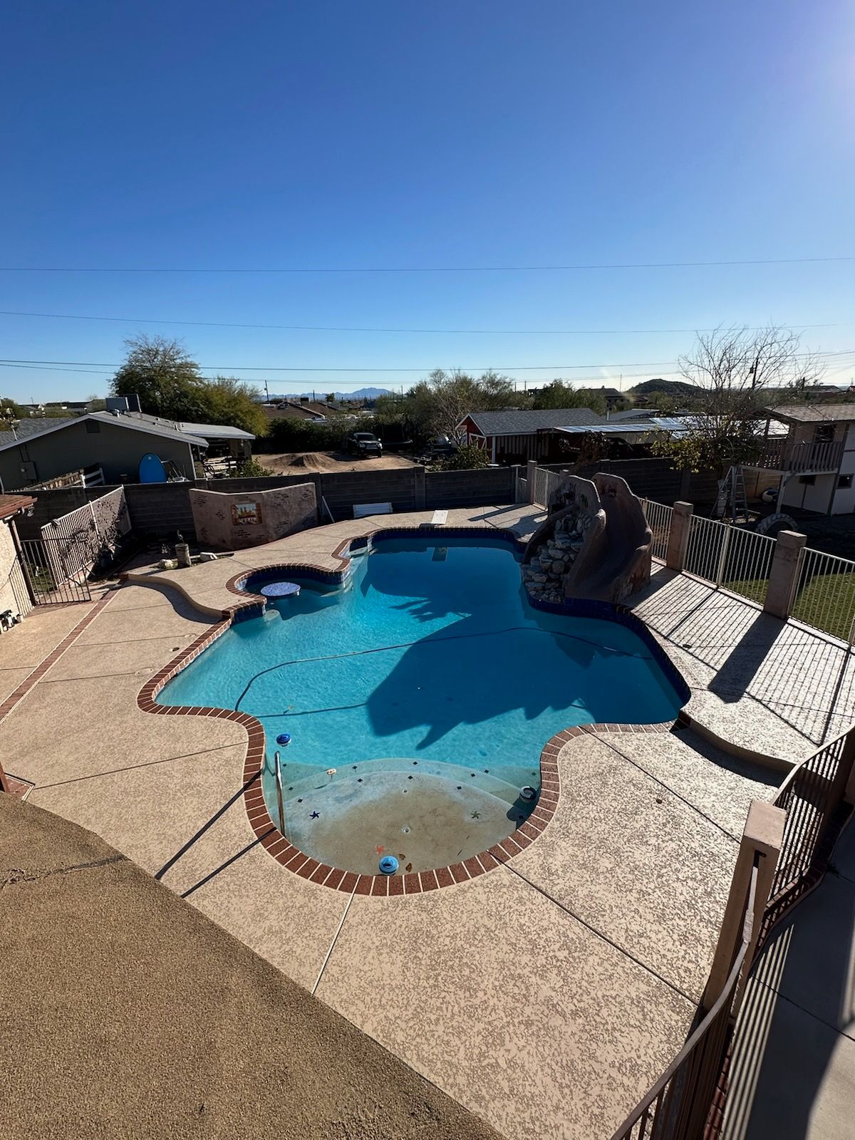 A large swimming pool with a slide in the backyard of a house.