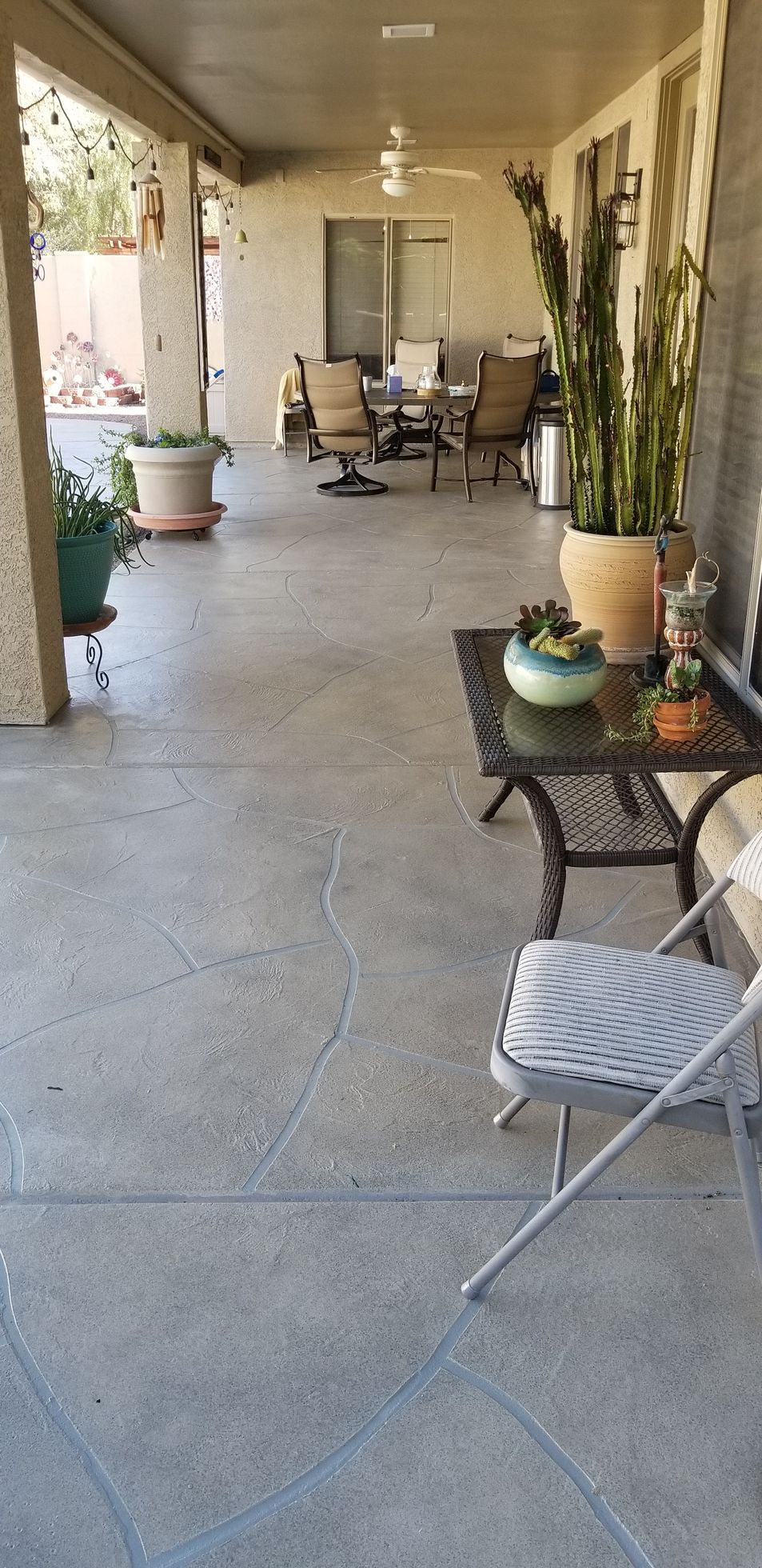A patio with a table and chairs and potted plants.
