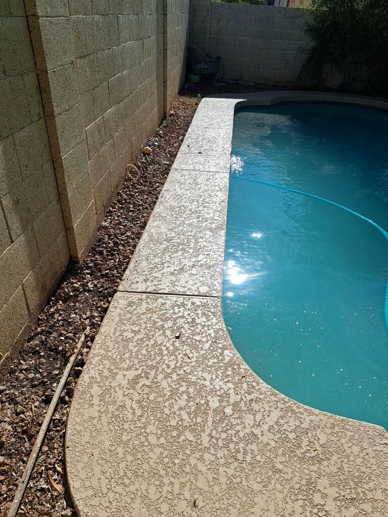 A swimming pool is surrounded by a brick wall and gravel.