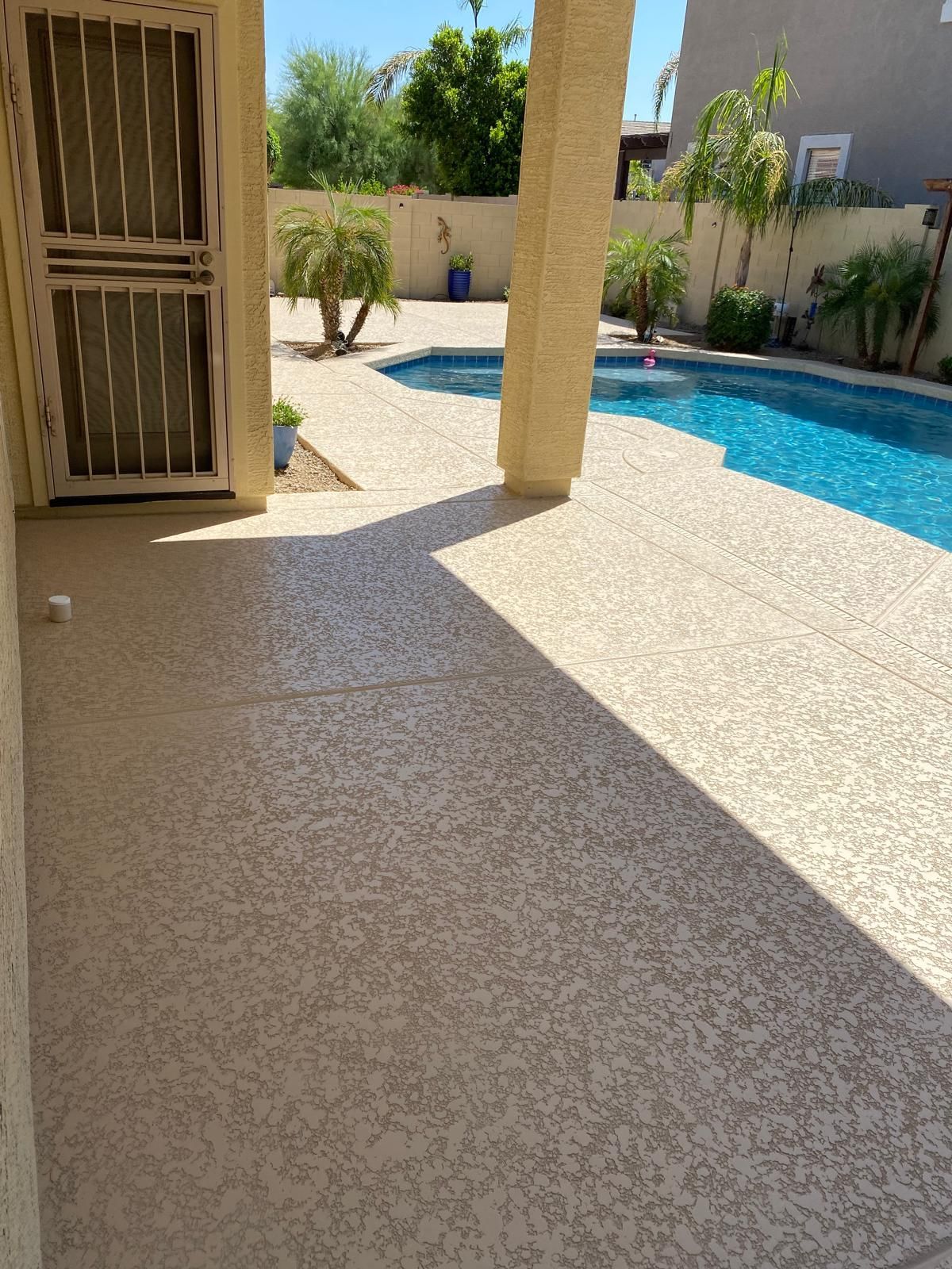 A patio with a swimming pool in the background
