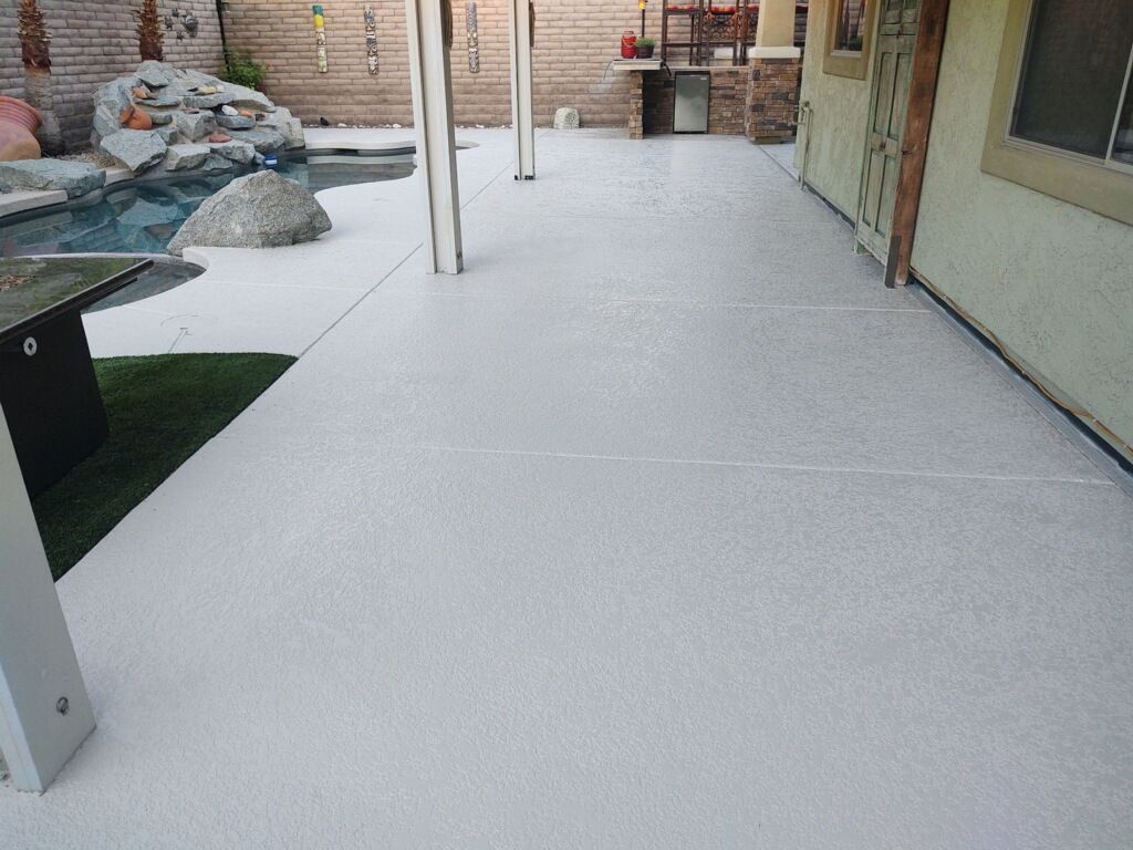 A white patio with a swimming pool in the background