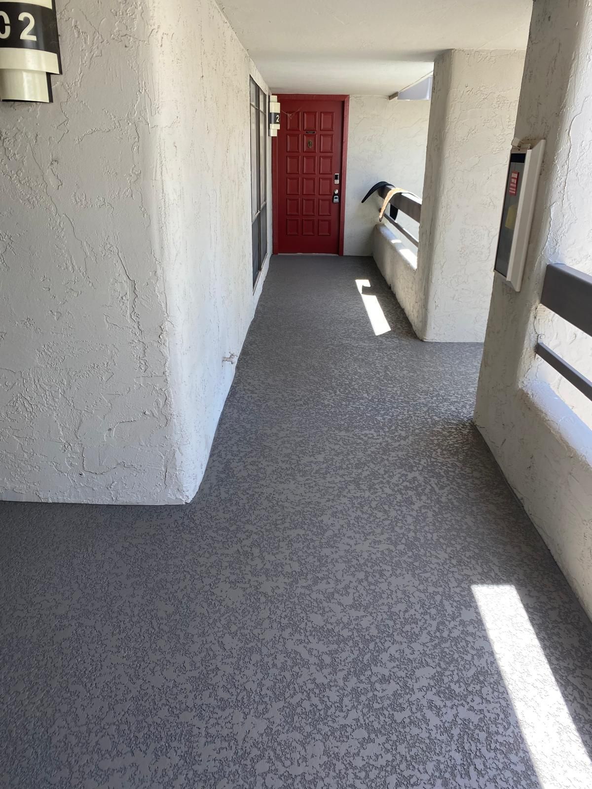 A hallway with a red door and a balcony in a building