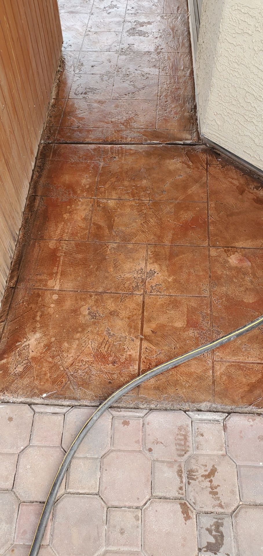 A hose is sitting on a tiled floor next to a wall