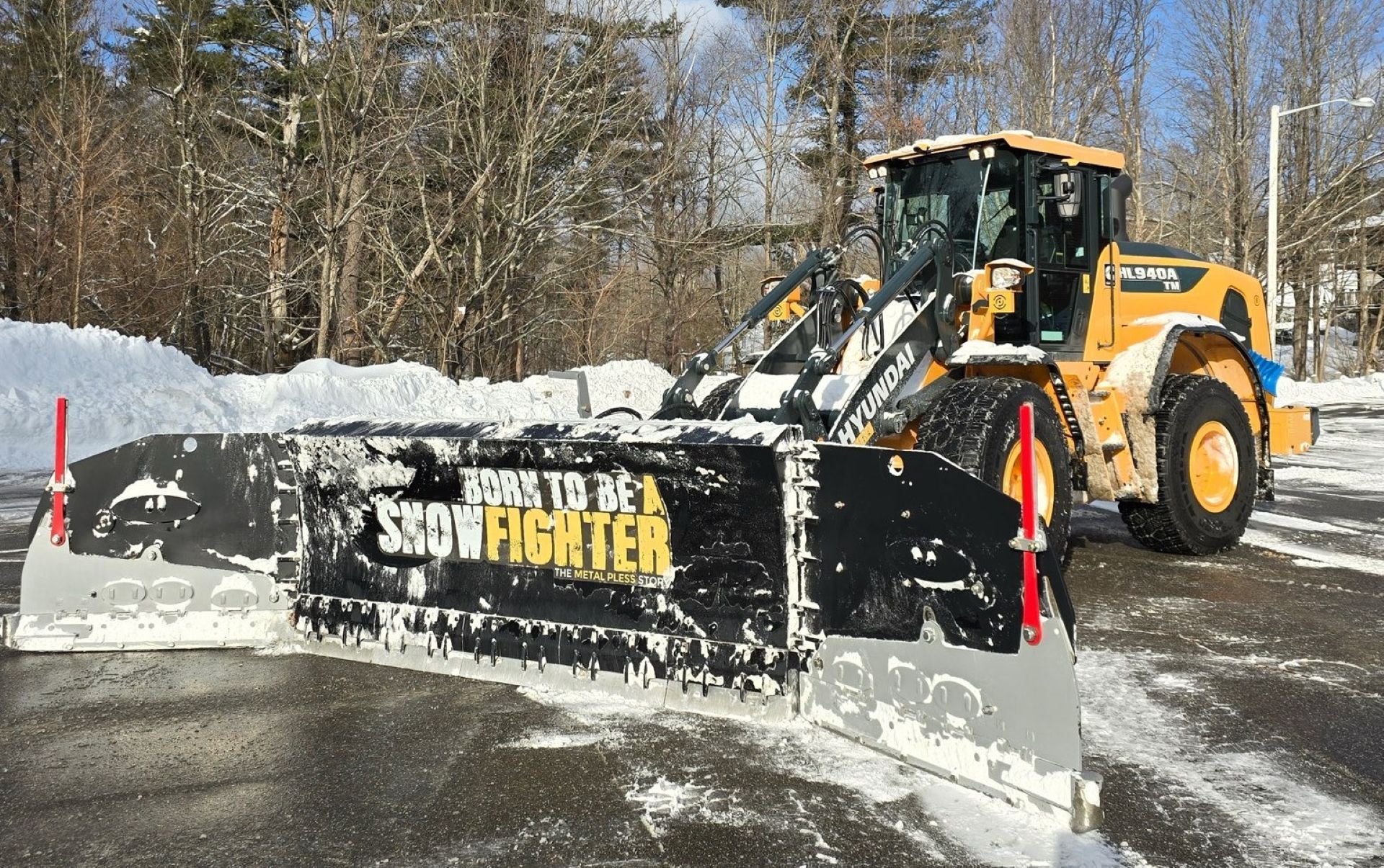 Yellow snowplow clearing a snow-covered parking lot with