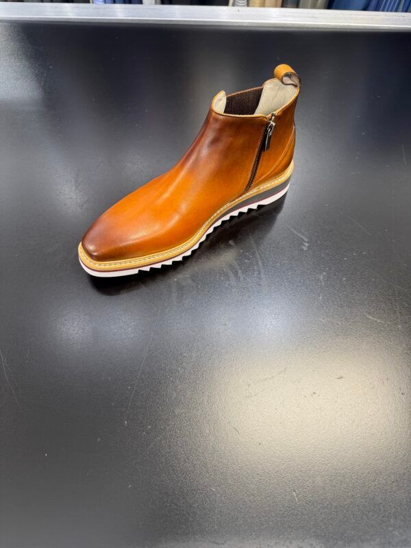 A brown leather boot is sitting on a black surface.