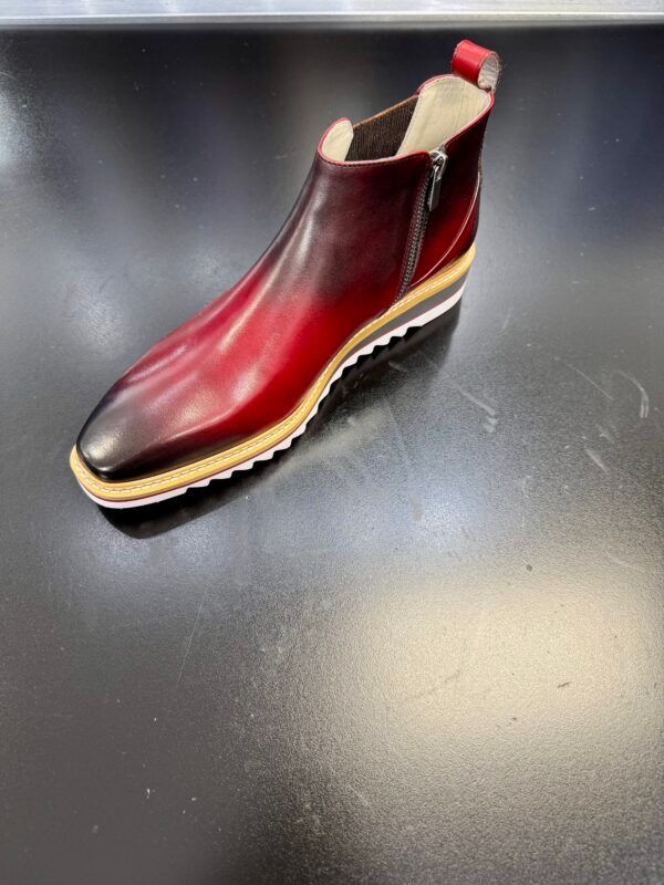 A pair of red leather boots are sitting on a black table.