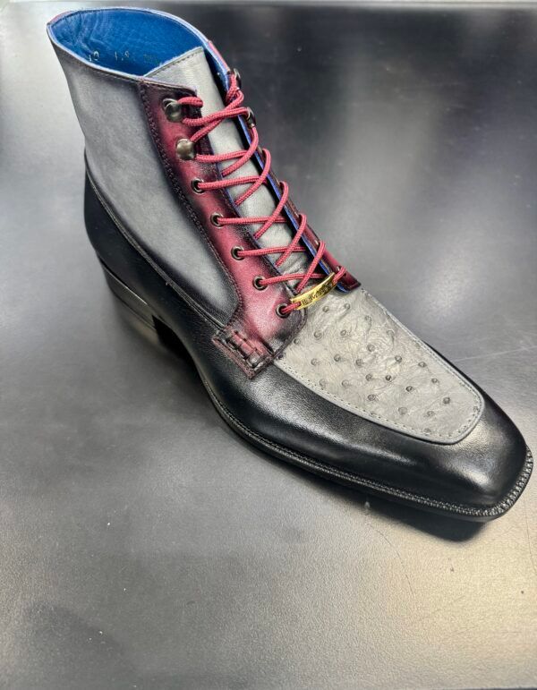 A black and white boot with red laces is sitting on a table.
