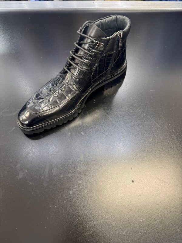 A black boot is sitting on top of a black table.