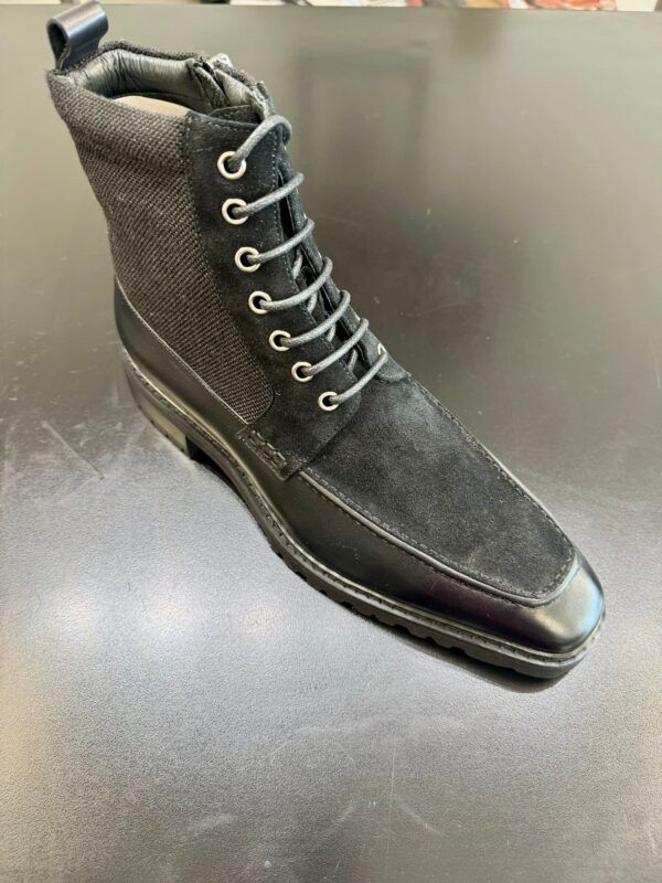 A pair of black boots are sitting on a black table.