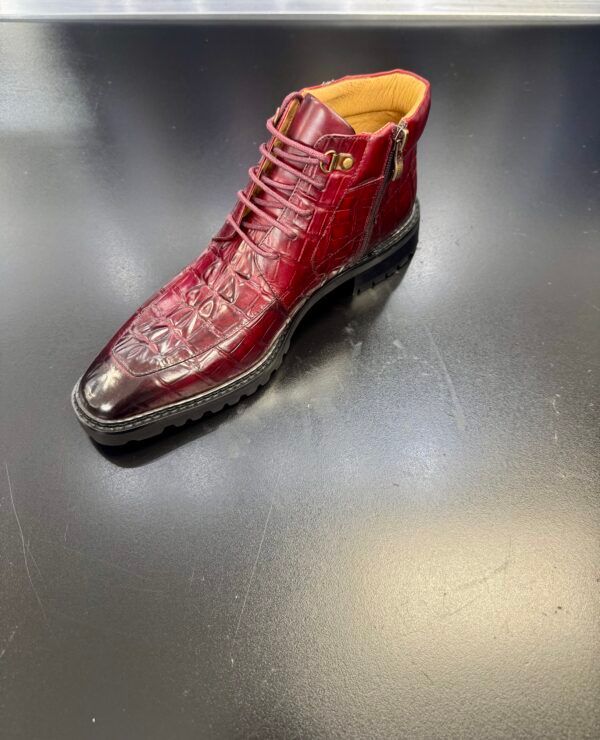 A red boot is sitting on top of a black table.