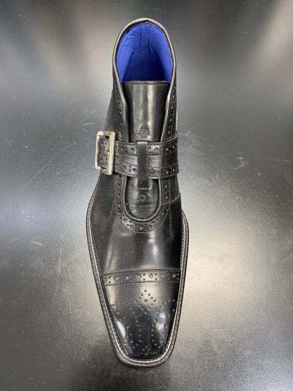 A pair of black shoes with a buckle on the side are sitting on a table.