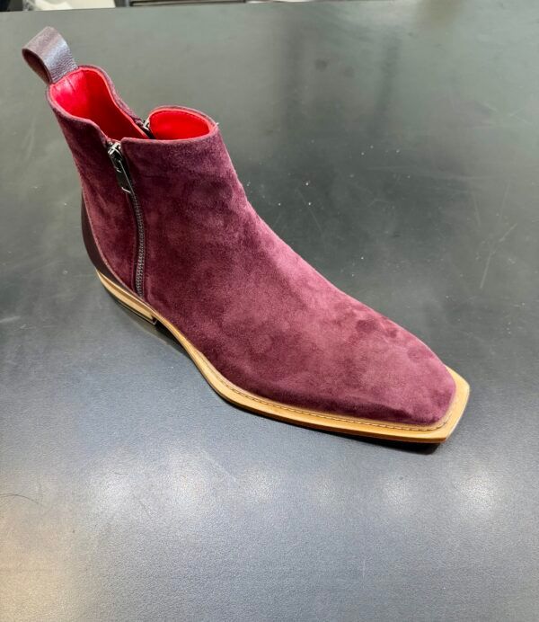 A pair of burgundy suede boots with a zipper on the side
