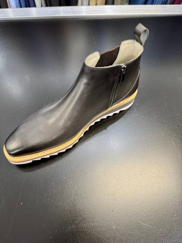 A black shoe is sitting on a black table.