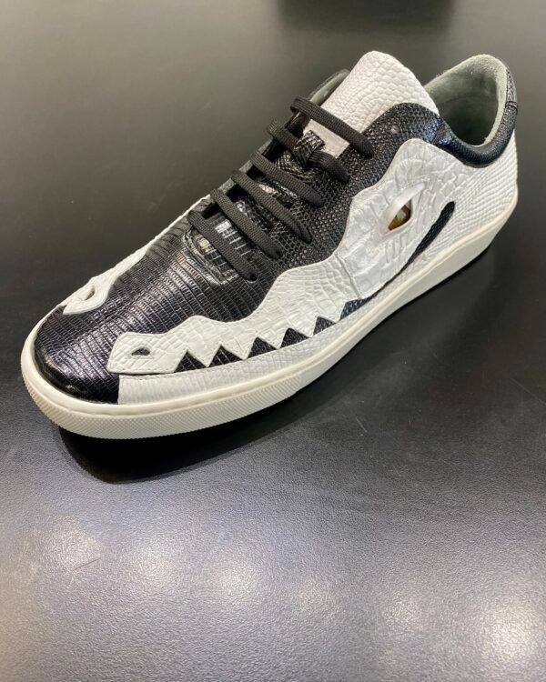 A pair of black and white sneakers with a crocodile design on the side.