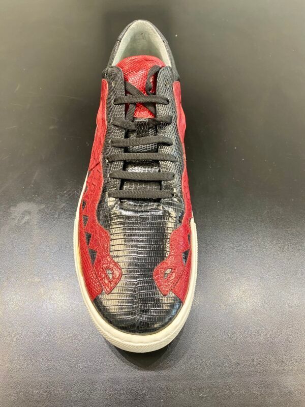 A pair of red and black sneakers on a black surface.
