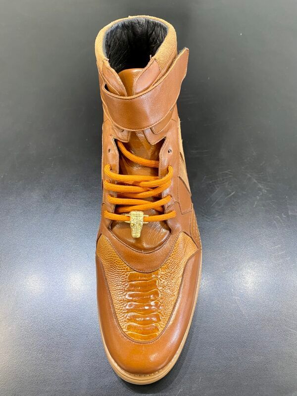 A pair of brown shoes with orange laces on a black surface.