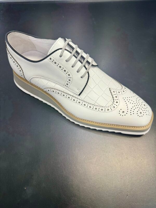 A pair of white shoes with black laces on a black surface