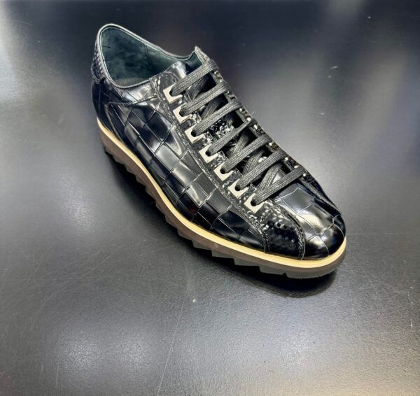A pair of black shoes with white laces on a black surface