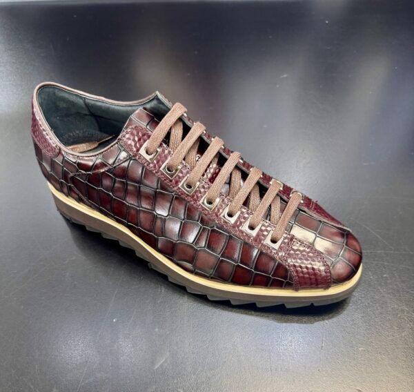 A pair of red shoes with brown laces on a black surface.