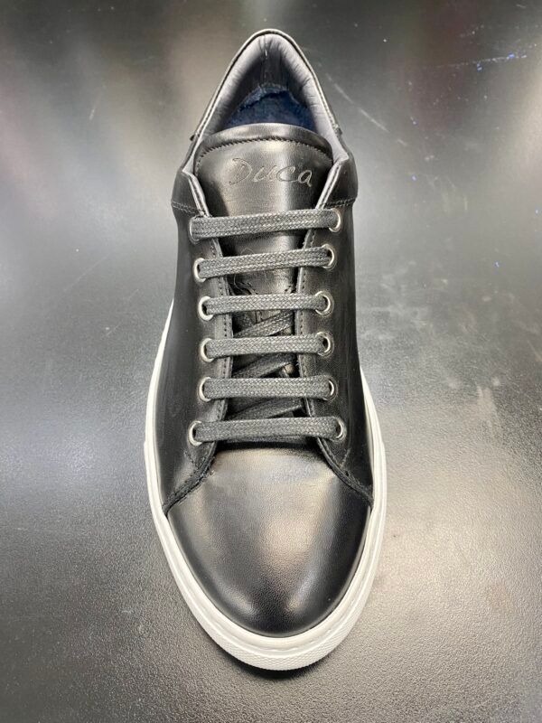 A pair of black sneakers with white soles are sitting on a table.