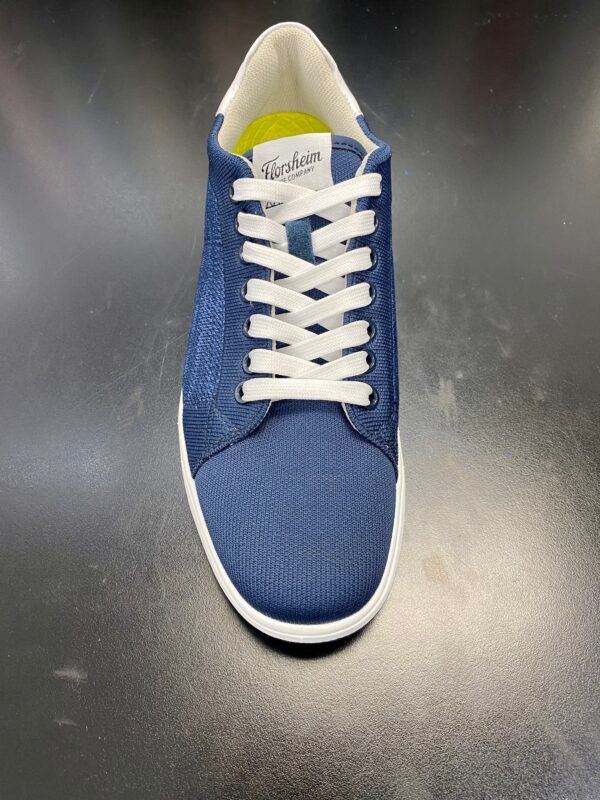 A pair of blue sneakers with white laces on a black surface.