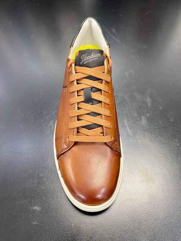 A pair of brown leather sneakers are sitting on a black surface.