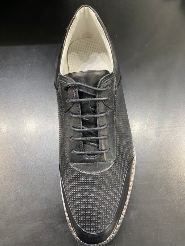 A pair of black shoes with white laces on a black surface.