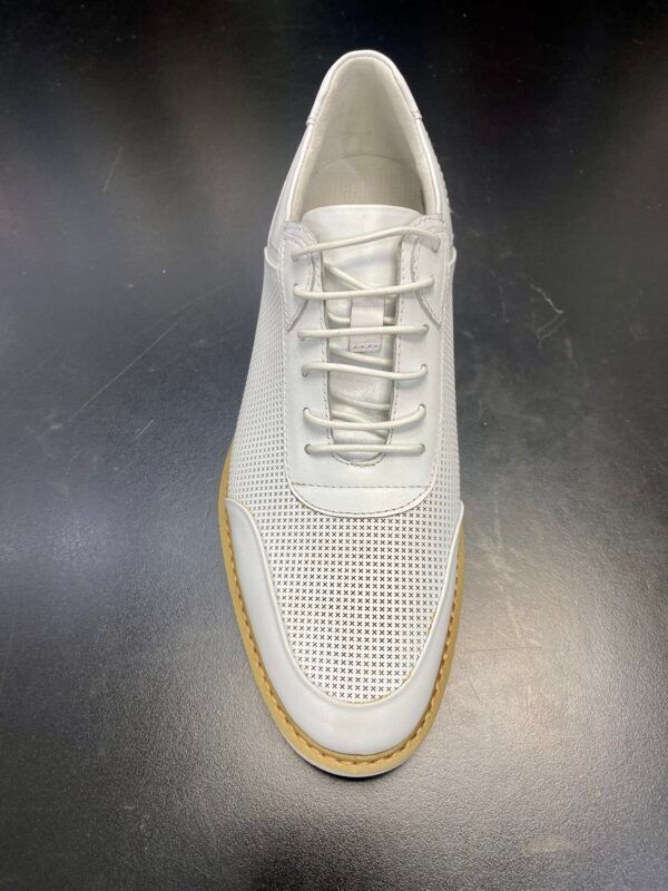 A pair of white shoes with laces on a black surface.