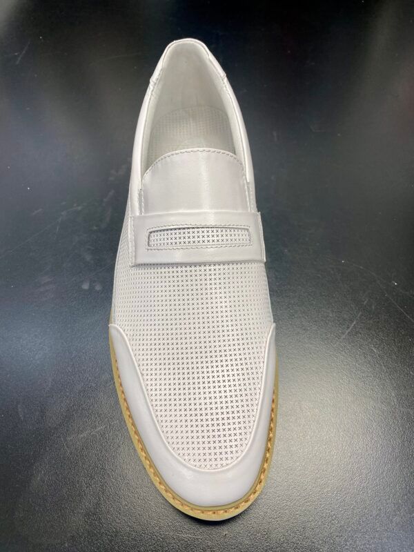 A pair of white shoes with holes in them are sitting on a table.