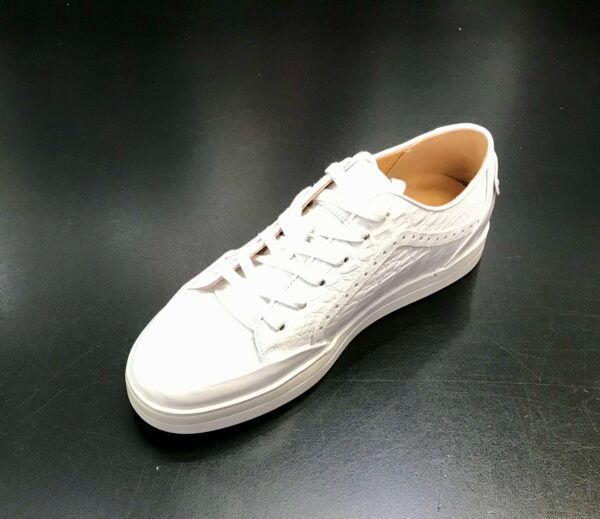 A pair of white sneakers on a black surface