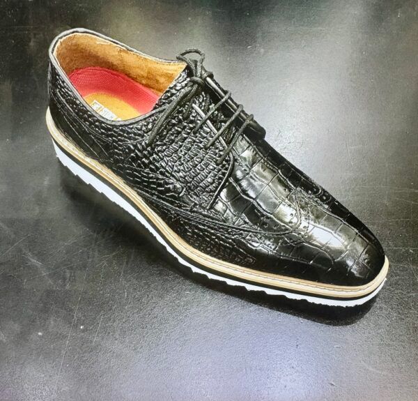 A black shoe with a crocodile pattern is sitting on a table.