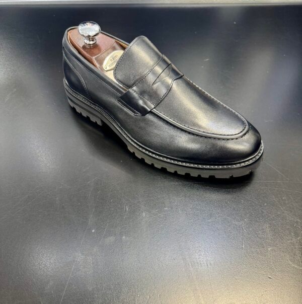 A pair of black loafers sitting on a black surface