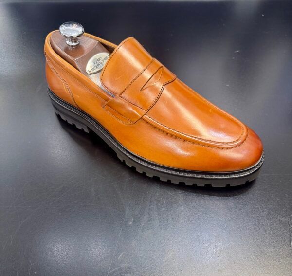 A pair of brown loafers sitting on top of a black table