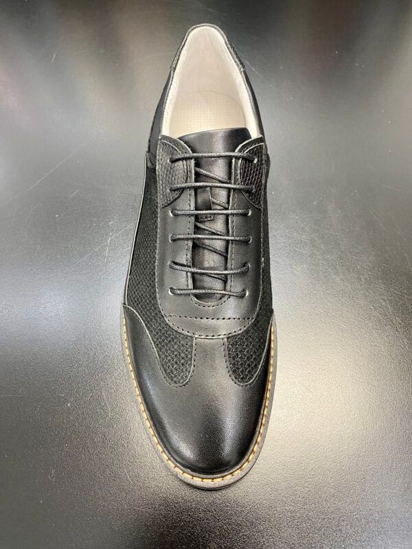 A pair of black shoes with laces on a black surface.