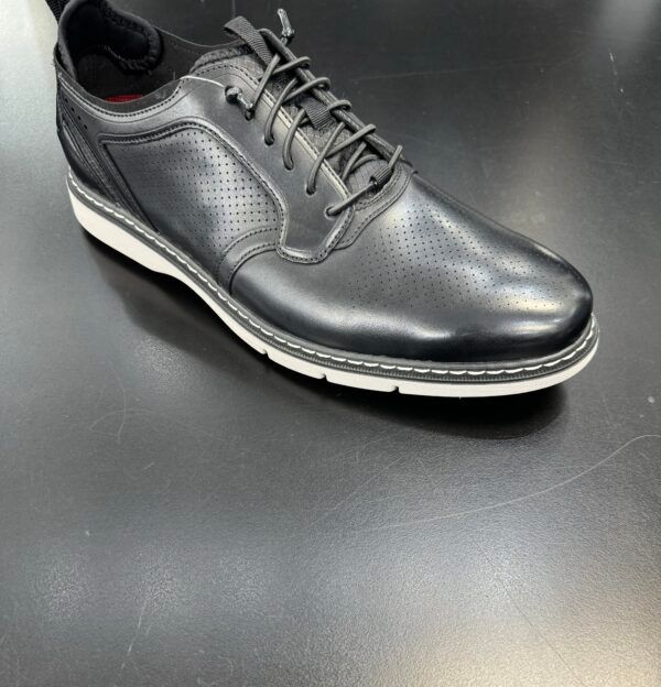 A pair of black shoes with white soles on a black surface